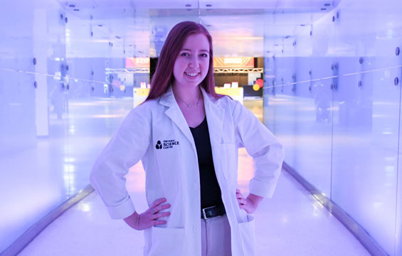 A woman in a Science Centre lab coat stands in a hallway.