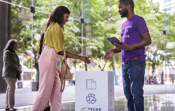 A woman puts a phone into a device recycling box.