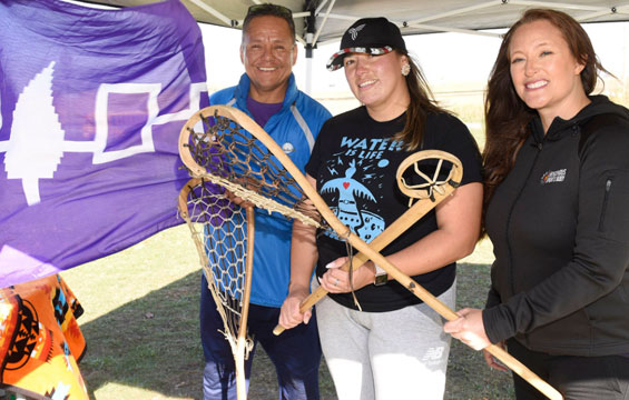 Three people holding lacrosse sticks.
