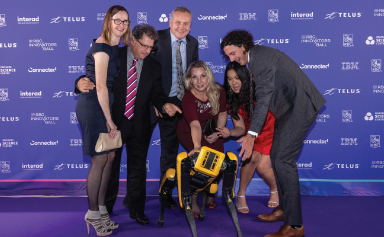A group of ball attendees pose with a robot dog.