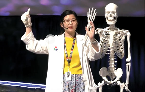 An educator holds up the hand of a skeleton