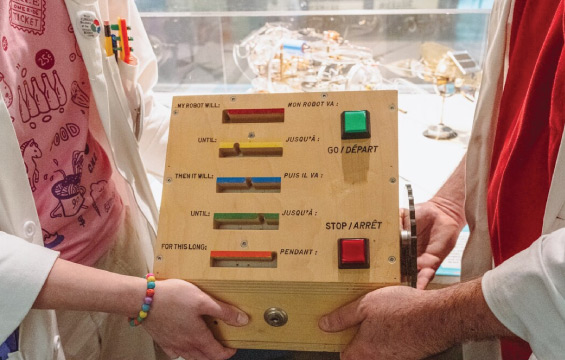 An interactive wooden panel with instructions to send to a robot. Includes a large green "GO" button and red "STOP" button.