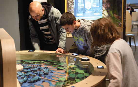 A man and two children engage with an exhibit in Climate Quest.