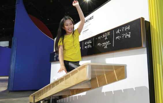 A student climbs on a big lever exhibit.