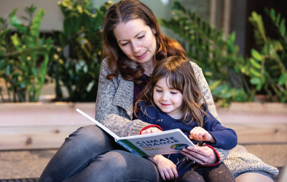 A woman reads a book called "Climate Change" with a child.