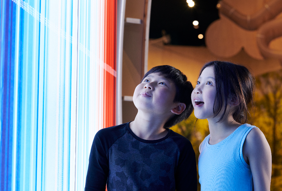 Deux enfants s'émerveillent devant un module d'exposition.