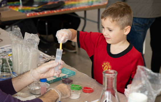 A boy conducting an experiment using litmus paper to check the pH level of water in a testube.
