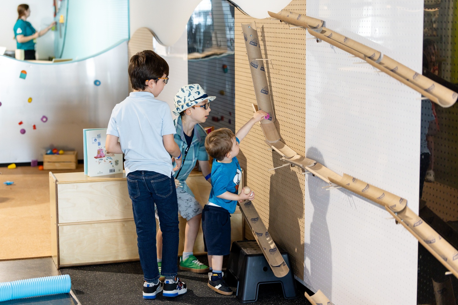 [Kids playing with the cardboard racing tracks at the Innovation Station.][Des enfants jouent avec les circuits de course en carton à la Station d'innovation.]