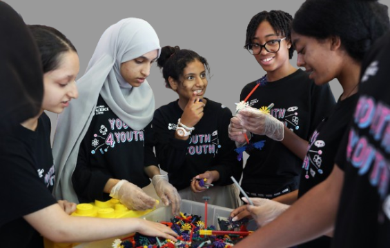 A group of youth girls playing with Lego blocks.