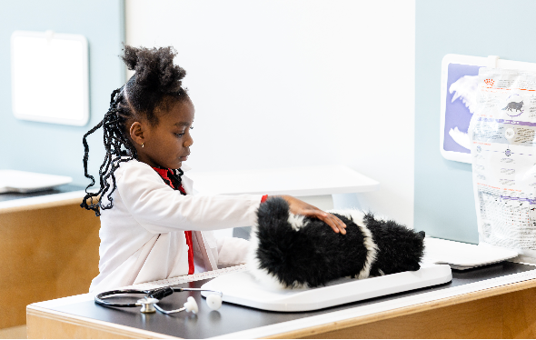 [A girl plays in the KidSpark vet clinic.][Une fille joue dans la clinique vétérinaire KidSpark.]