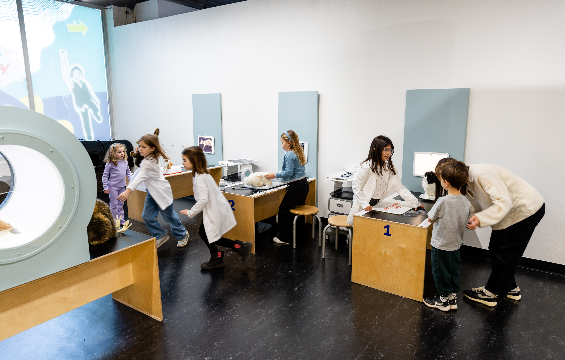 A group of kids playing at the doctor's table with toys in the Health Hub.
