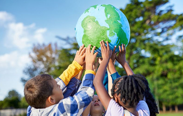 A group of children hold a globe up high.