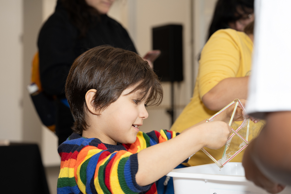 a child in a rainbow sweater does a science experiment.