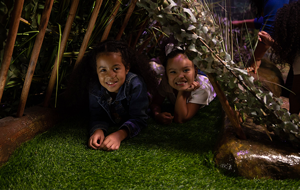Two kids lie under a shelter.