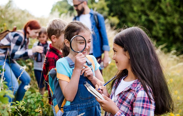 A girl looks at her friend through a magnifying glass.