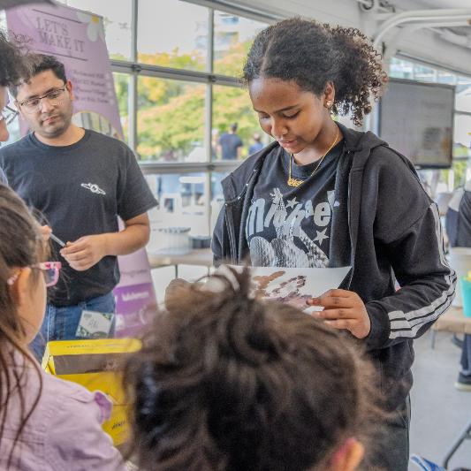 A young woman looks down at a poster.