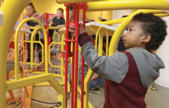 A child moves a ball in the Rhodes Sculpture in KidSpark.