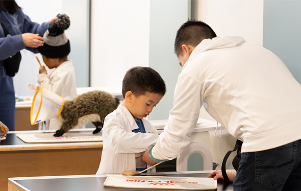 Two kids and their parents play in the KidSpark vet clinic