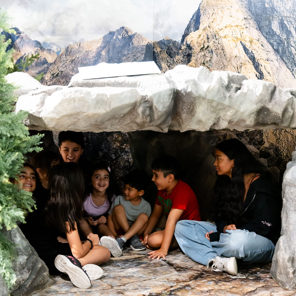 A group of kids sitting inside the cave.
