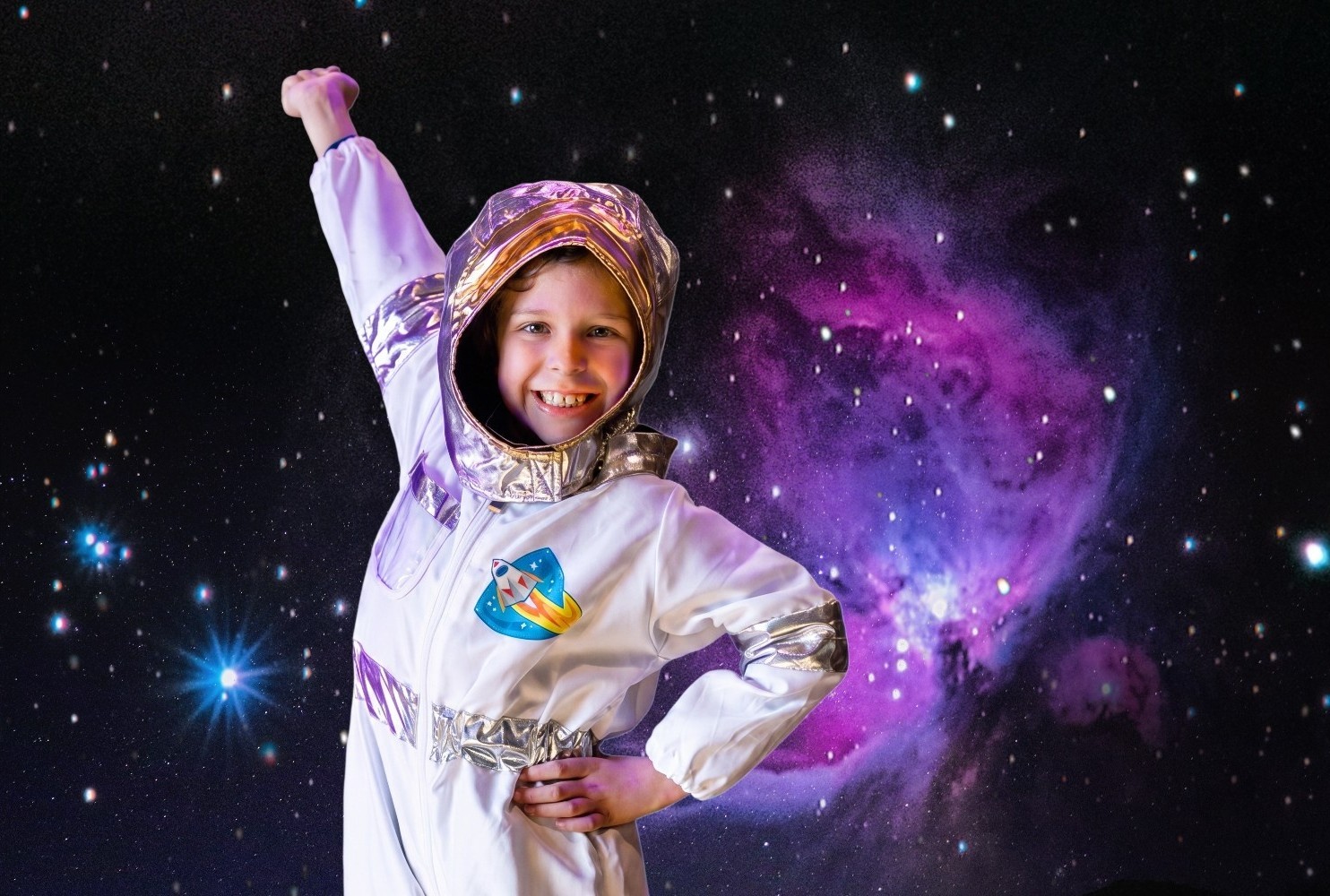 A kid wearing a space suit enacting to fly.