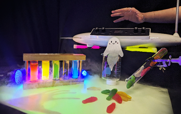 Colourful, glowing objects are laid out on a table as a hand reaches in.