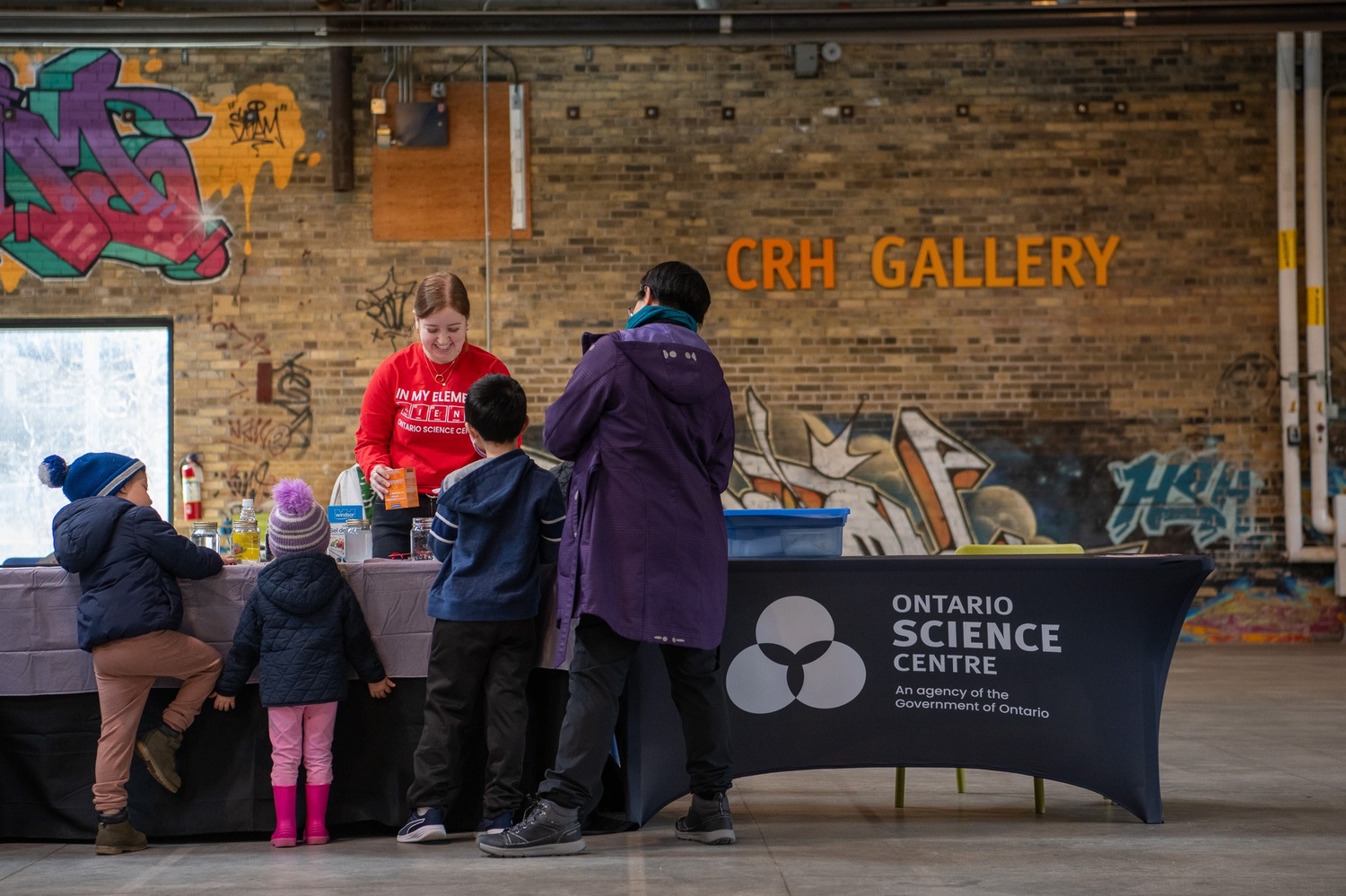 A family of four and a science centre staff do a science experiment.