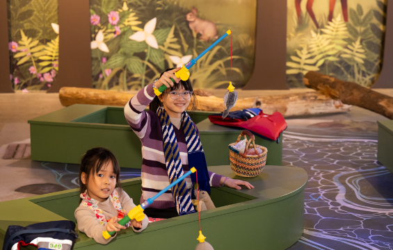 Two girls playing with the fishing rods at the pond.