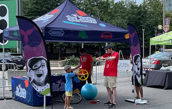 A child and two Ontario Science Centre staff play at the Jr. Jays pop up booth.
