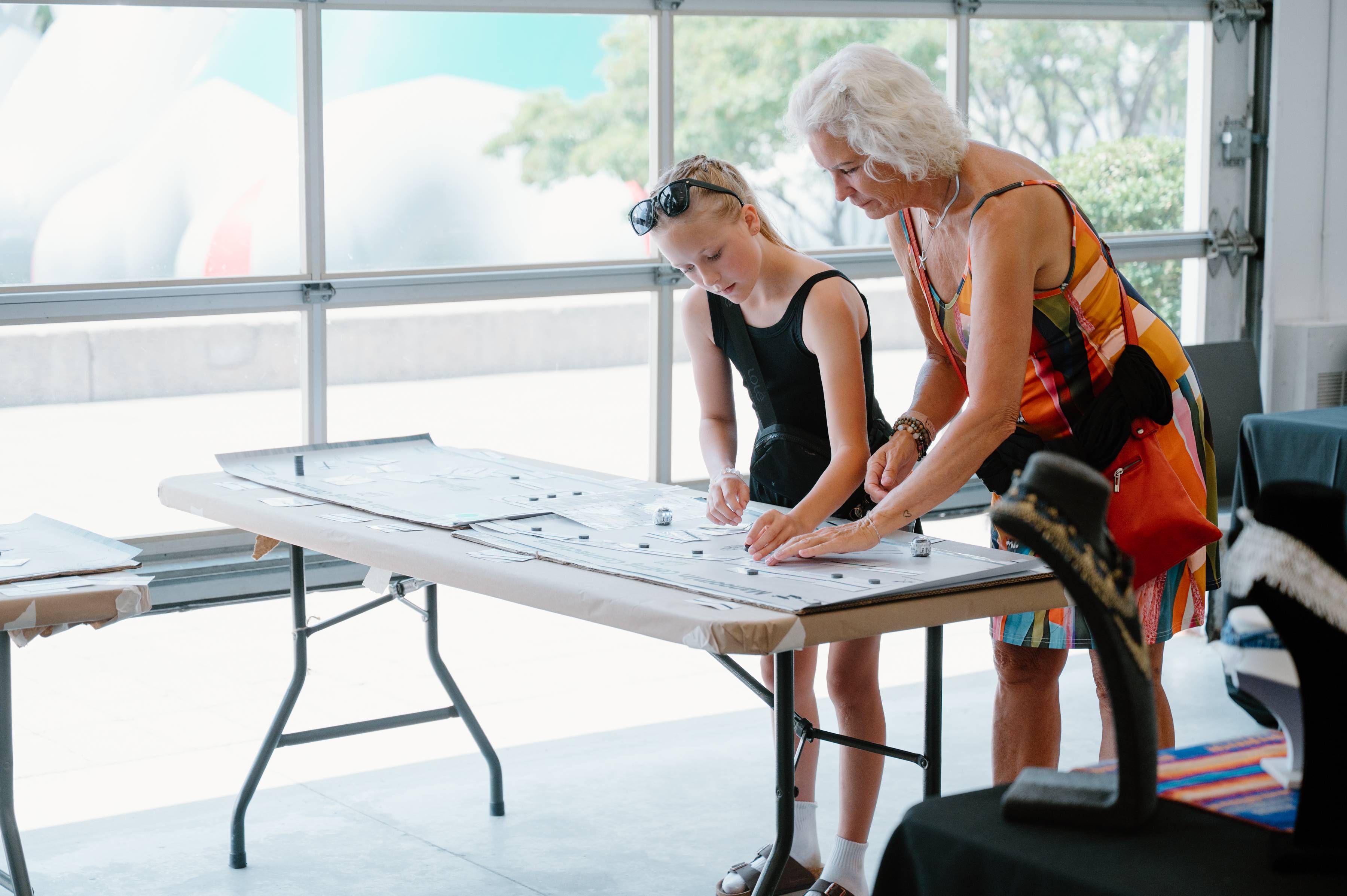 A young girl an older woman stand over a table.