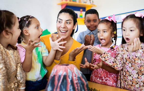 A teacher does a volcano experiment with 5 excited kids.