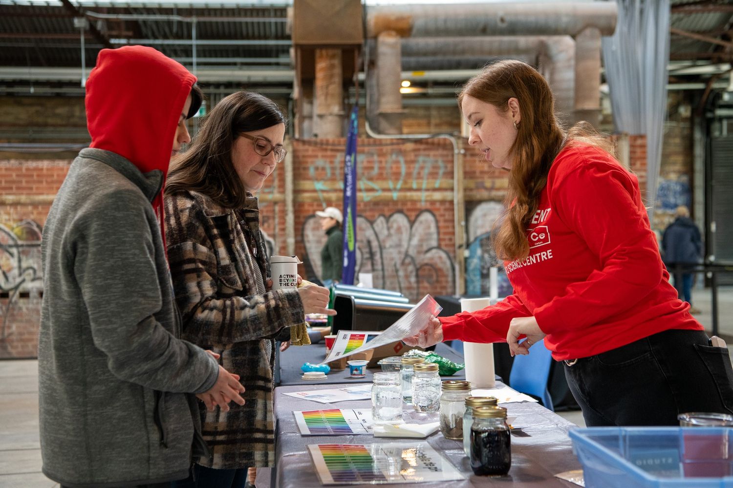 Three people stand over an event booth 