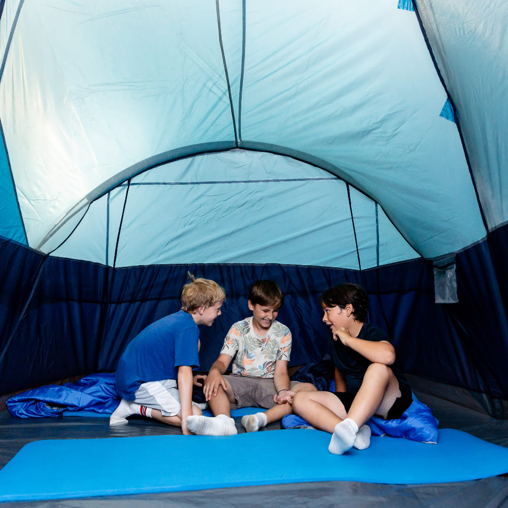 A group of boys playing under a camping tent.