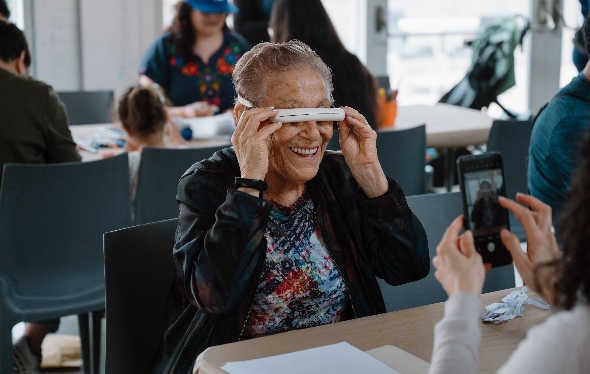 Someone takes a photo of a woman holding up sunglasses to her face.