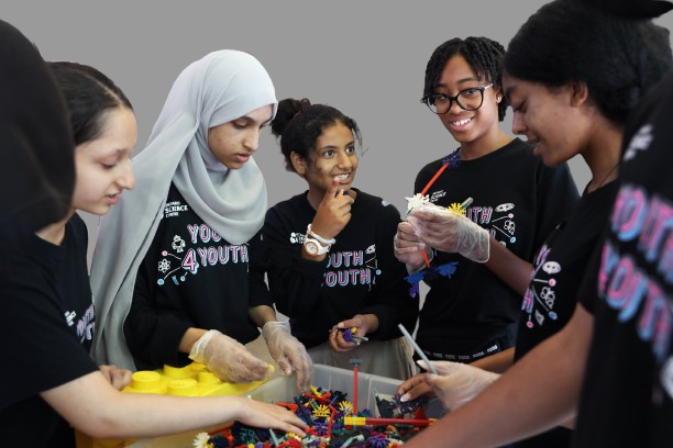 A group of youth girls playing with Lego blocks.
