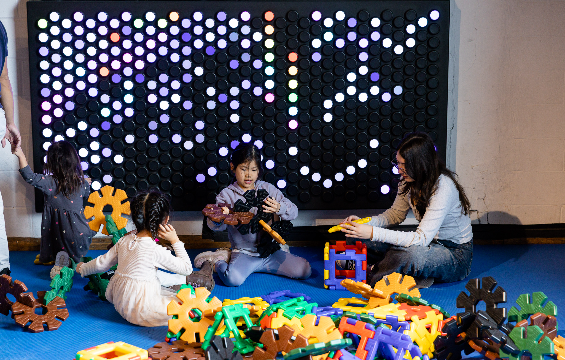 A group of kids and their guardians playing with blocks in the KidSpark.