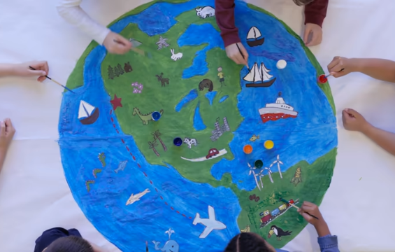 Kids painting a large earth shaped globe on paper.