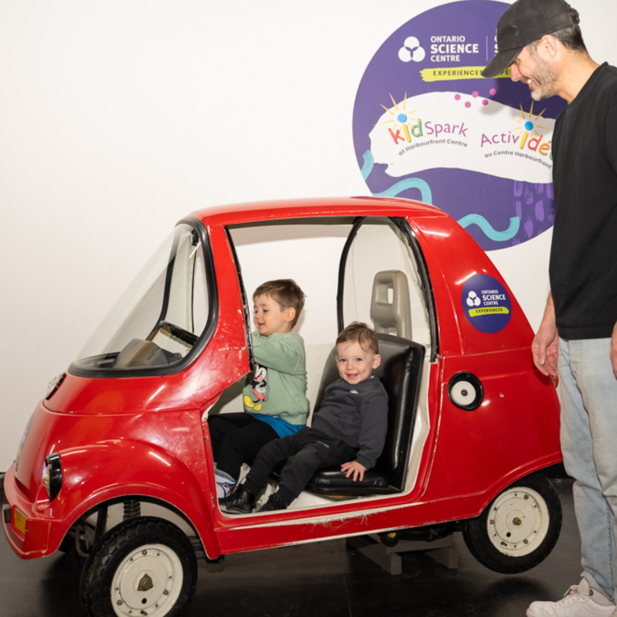 Two kids sitting inside the toy car.