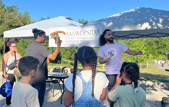 Three kids and three adults interact with the sauropsida booth.