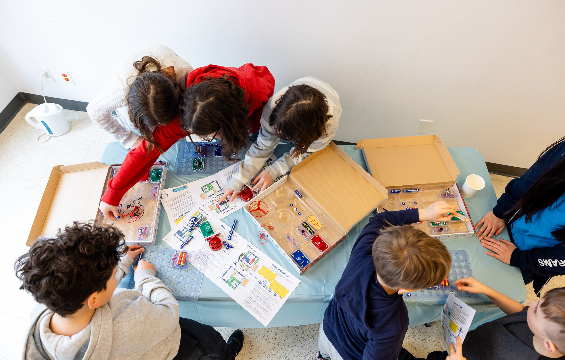 [A group of kids playing with robotics kits.][Un groupe d'enfants qui jouent avec des kits de robotique.]