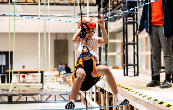 A boy well harnessed and playing on the rope course.